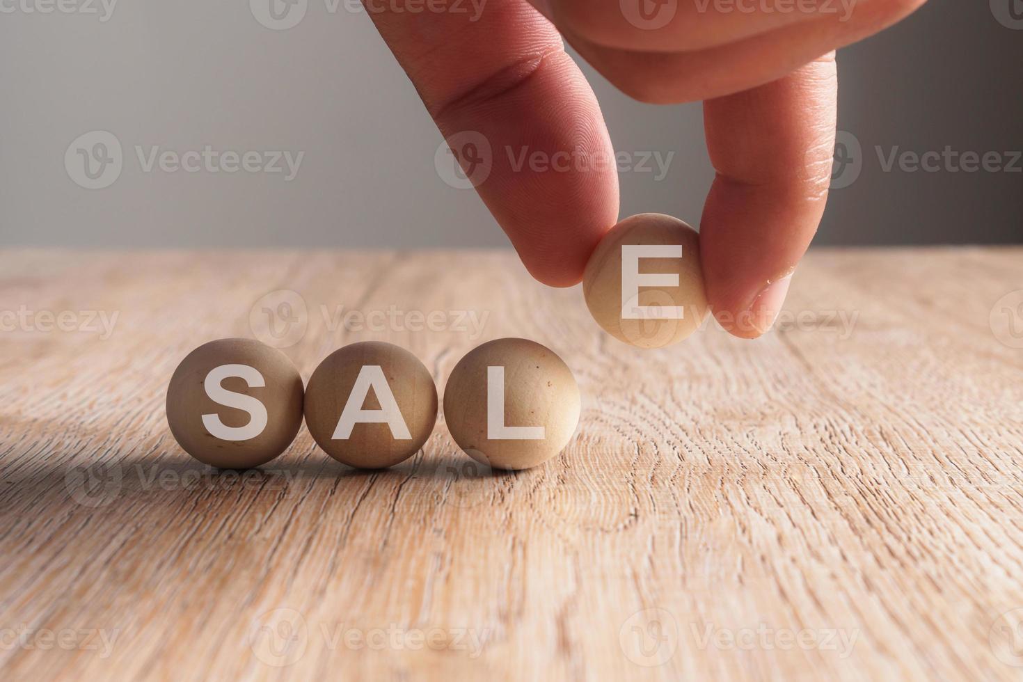 Hand putting on sale word written in wooden ball photo