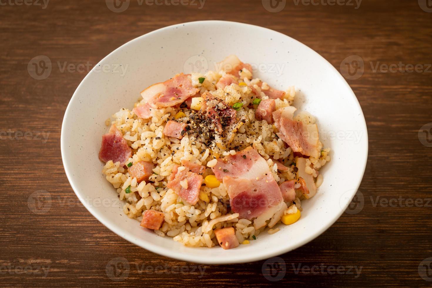 Arroz frito con tocino, jamón y pimientos negros en la placa blanca. foto