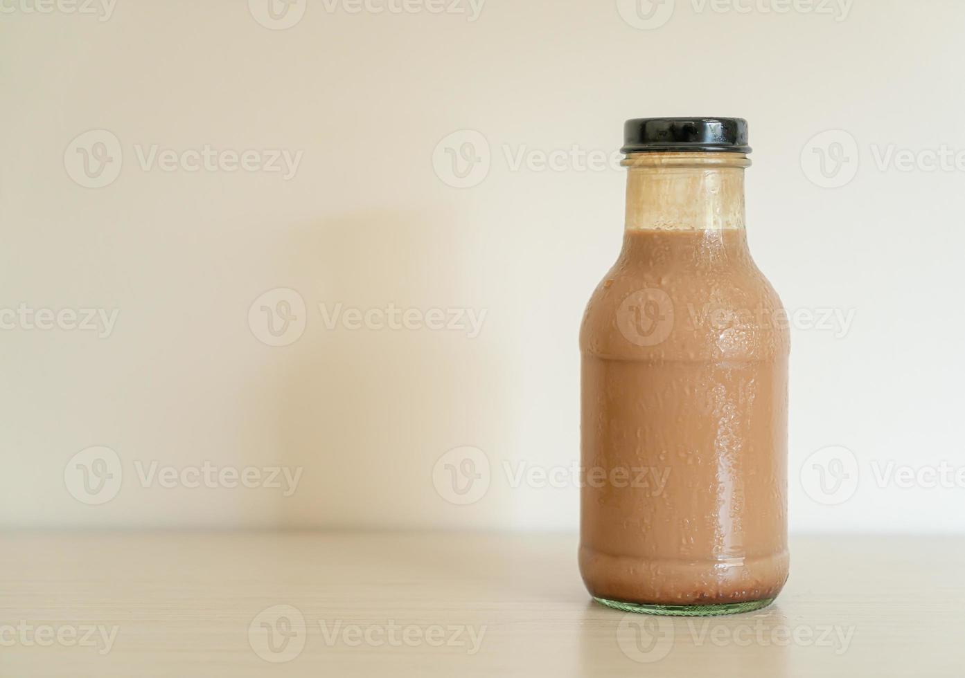 Leche con chocolate en botella de vidrio en la mesa foto