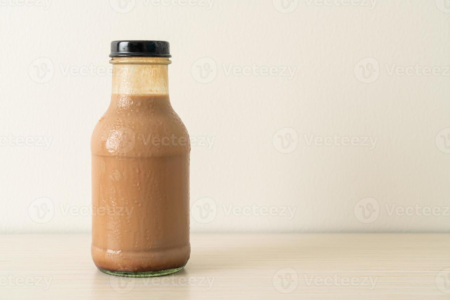 Leche con chocolate en botella de vidrio en la mesa foto