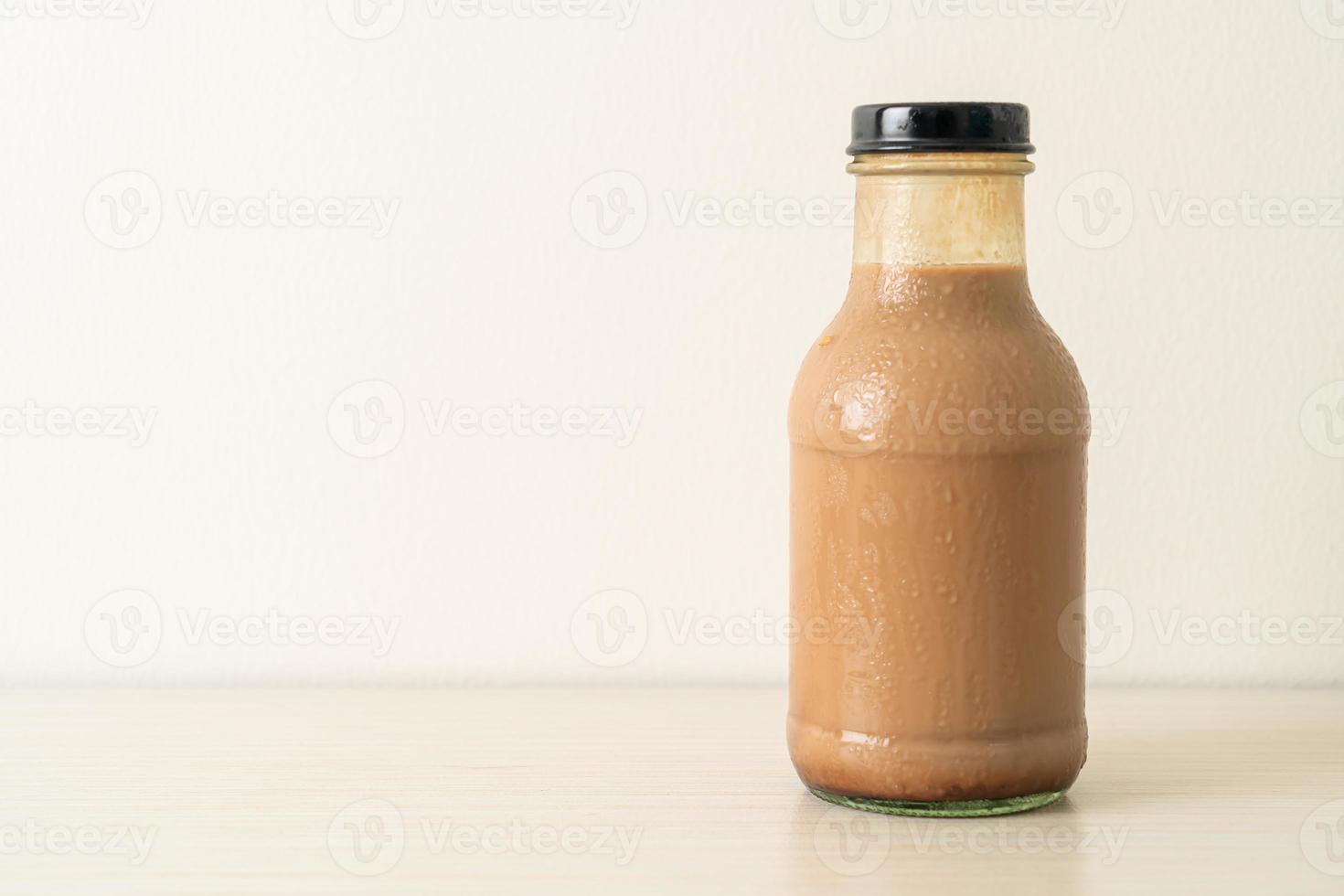 Leche con chocolate en botella de vidrio en la mesa foto