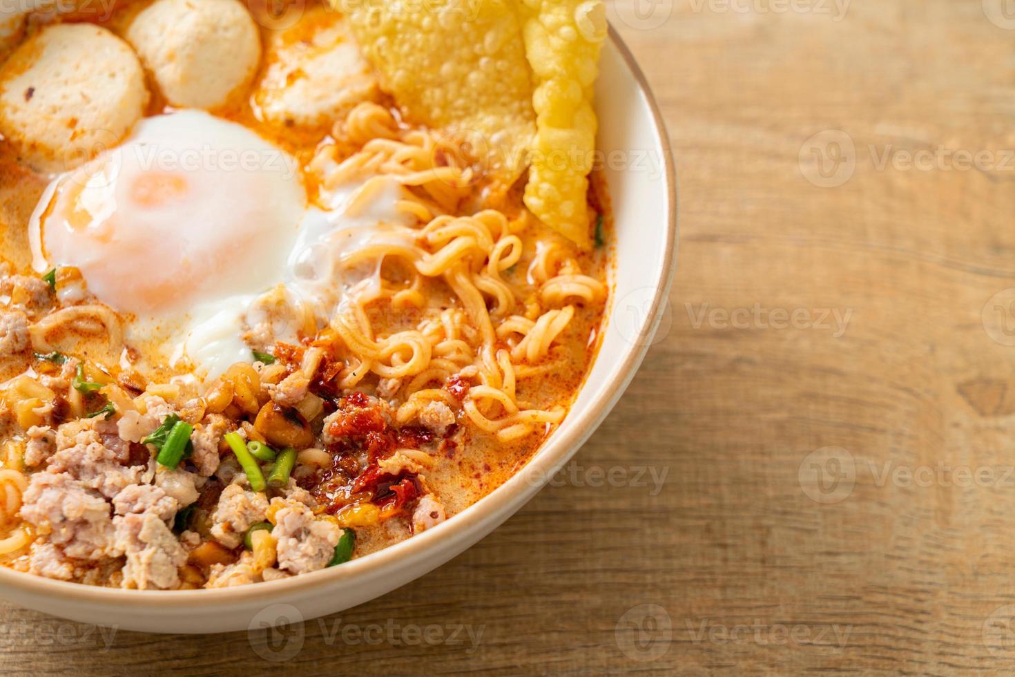 fideos instantáneos con carne de cerdo y albóndigas en sopa picante o fideos tom yum al estilo asiático foto