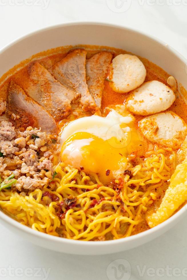 fideos de huevo con carne de cerdo y albóndigas en sopa picante o fideos tom yum al estilo asiático foto