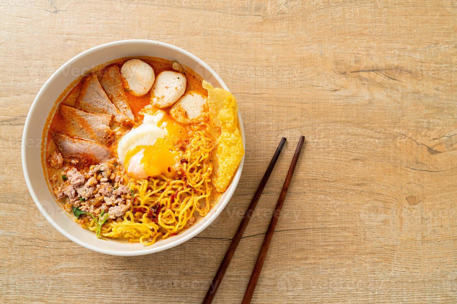 fideos de huevo con carne de cerdo y albóndigas en sopa picante o fideos tom yum al estilo asiático foto