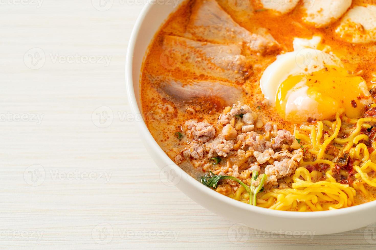 fideos de huevo con carne de cerdo y albóndigas en sopa picante o fideos tom yum al estilo asiático foto