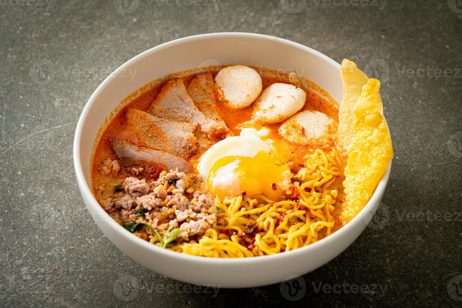 fideos de huevo con carne de cerdo y albóndigas en sopa picante o fideos tom yum al estilo asiático foto