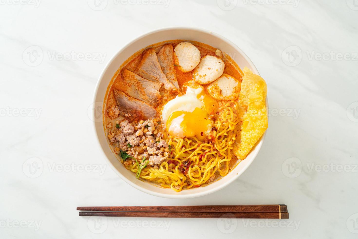 fideos de huevo con carne de cerdo y albóndigas en sopa picante o fideos tom yum al estilo asiático foto