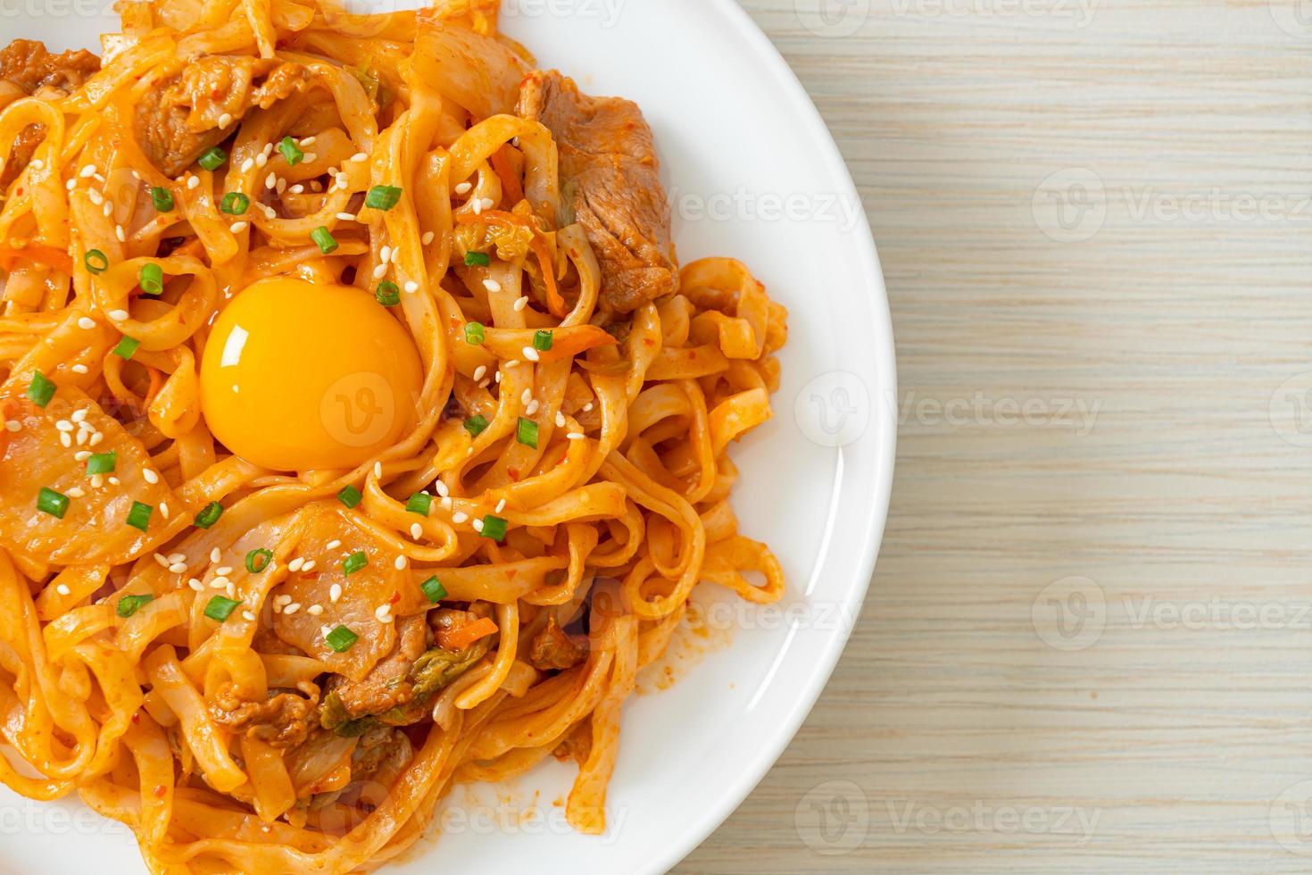 Stir-fried udon noodles with kimchi and pork - Korean food style photo