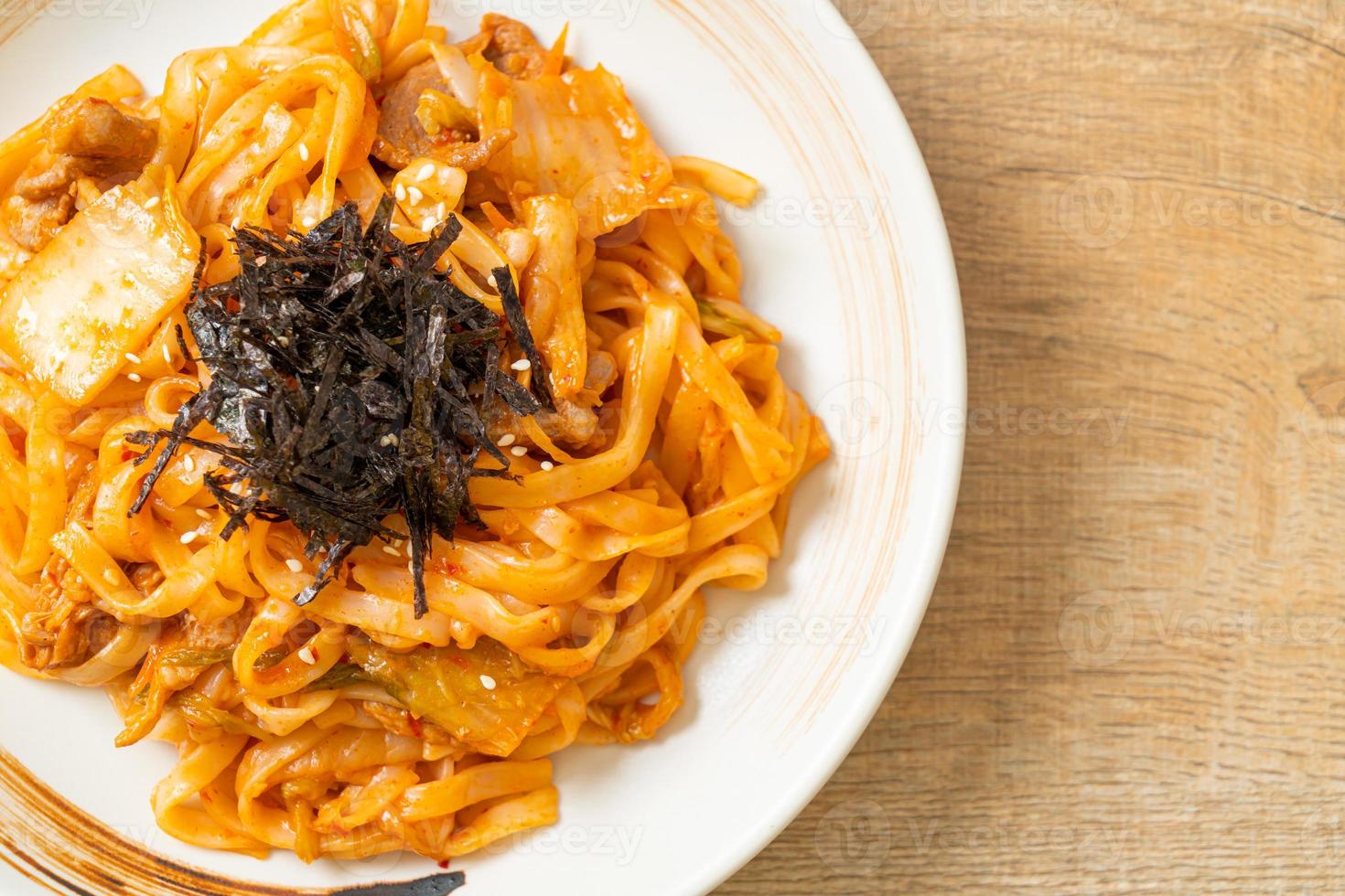 Stir-fried udon noodles with kimchi and pork - Korean food style photo