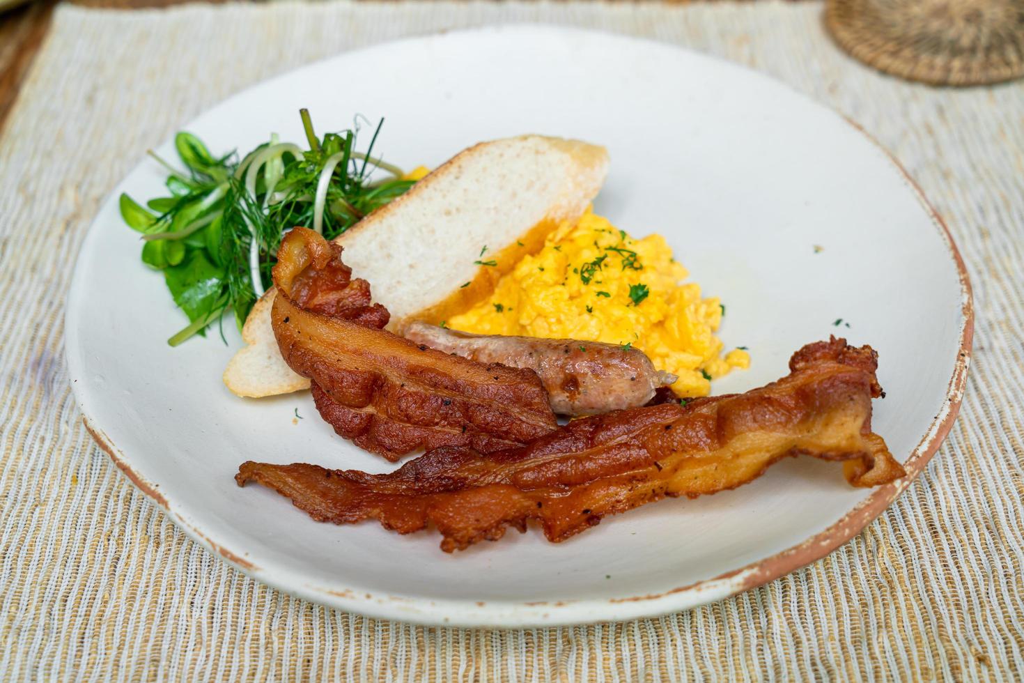 revuelve egga con tocino y salchichas en un plato para el desayuno foto