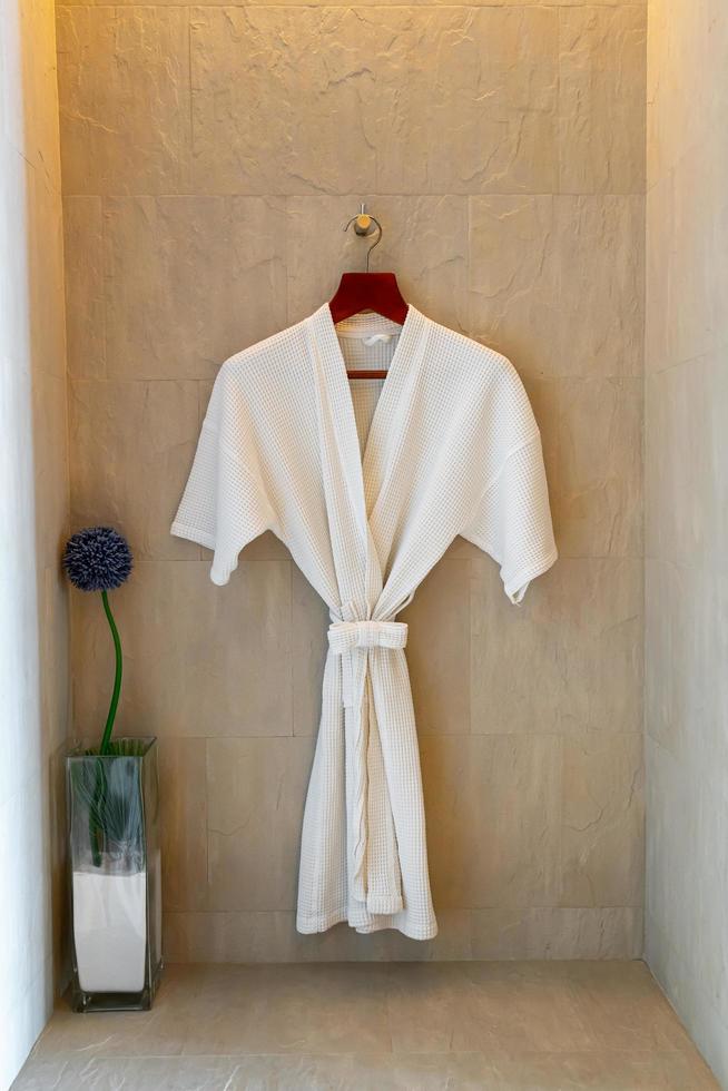 White bathrobe hanging on wall in bathroom photo