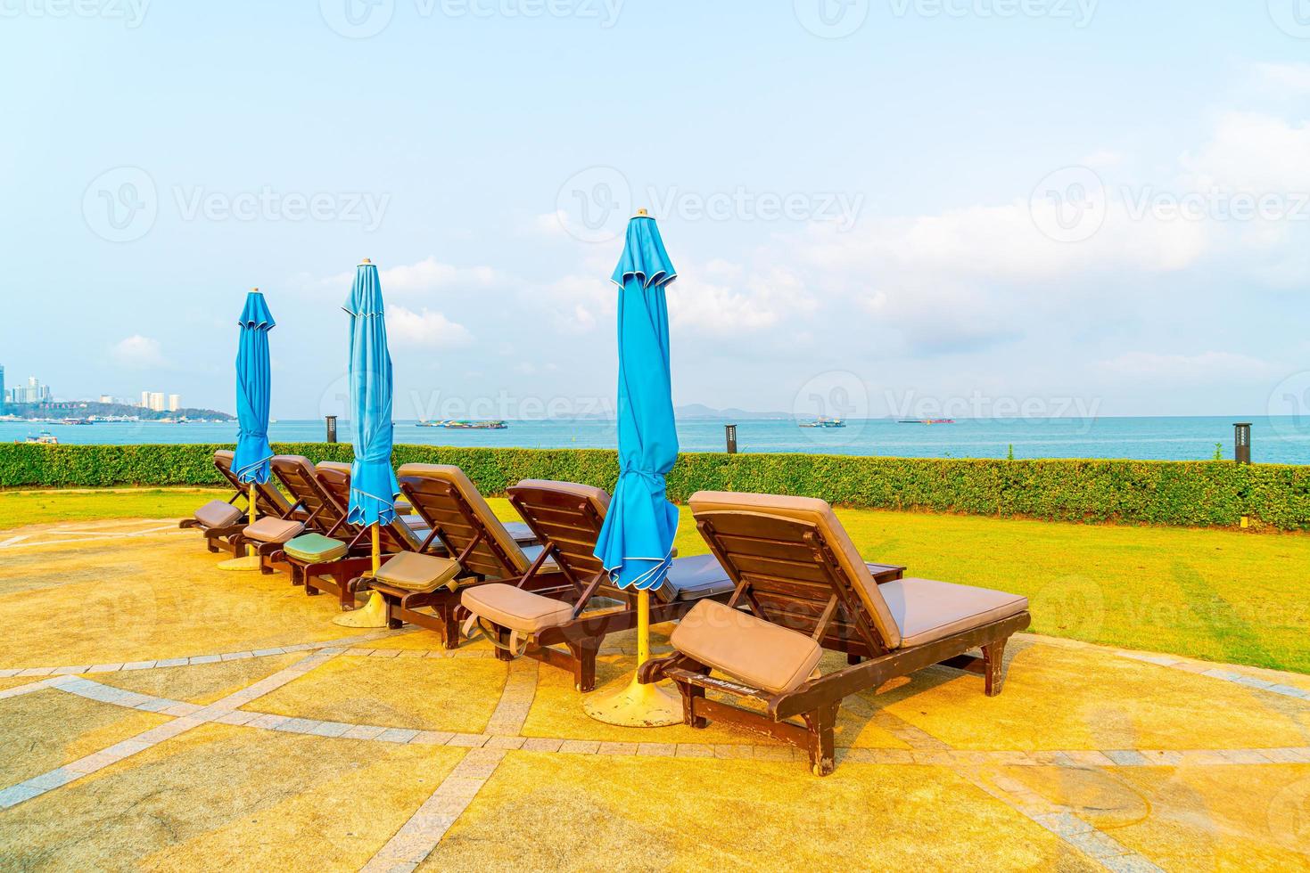 Silla de piscina y sombrilla alrededor de la piscina con fondo de mar océano foto