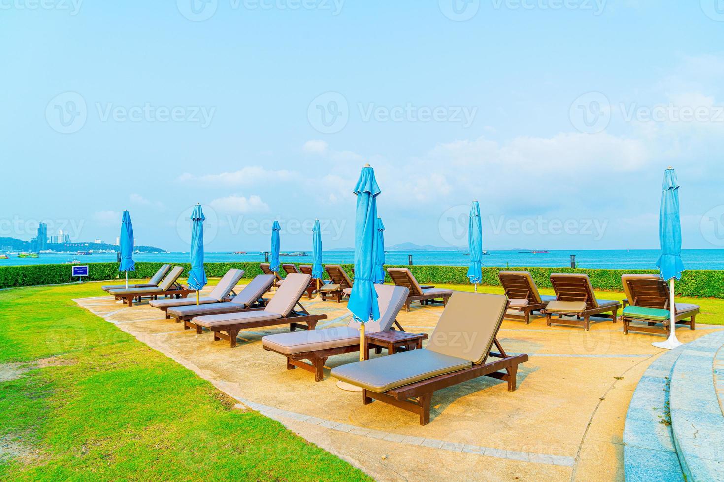 Silla de piscina y sombrilla alrededor de la piscina con fondo de mar océano foto