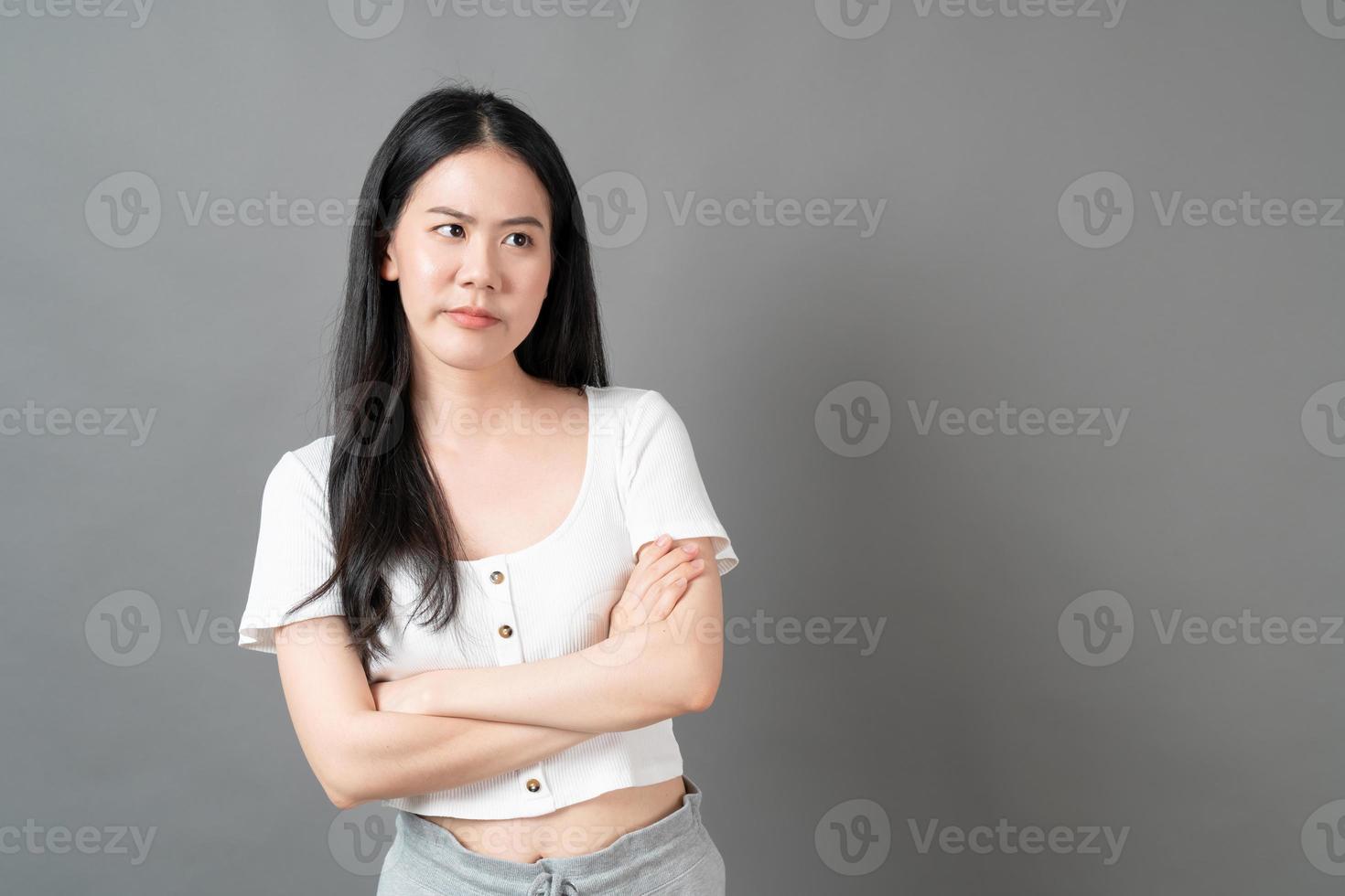 Young Asian woman with sulk face in white shirt on grey background photo