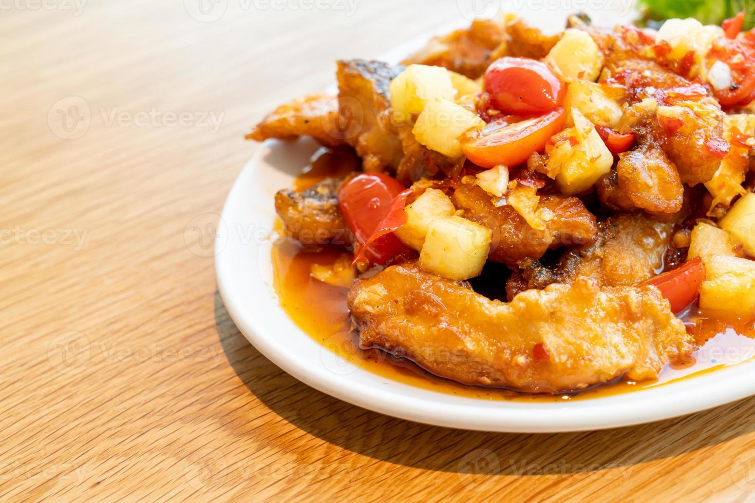 Pescado mero frito cubierto con salsa agridulce y picante en un plato blanco - estilo de comida asiática foto