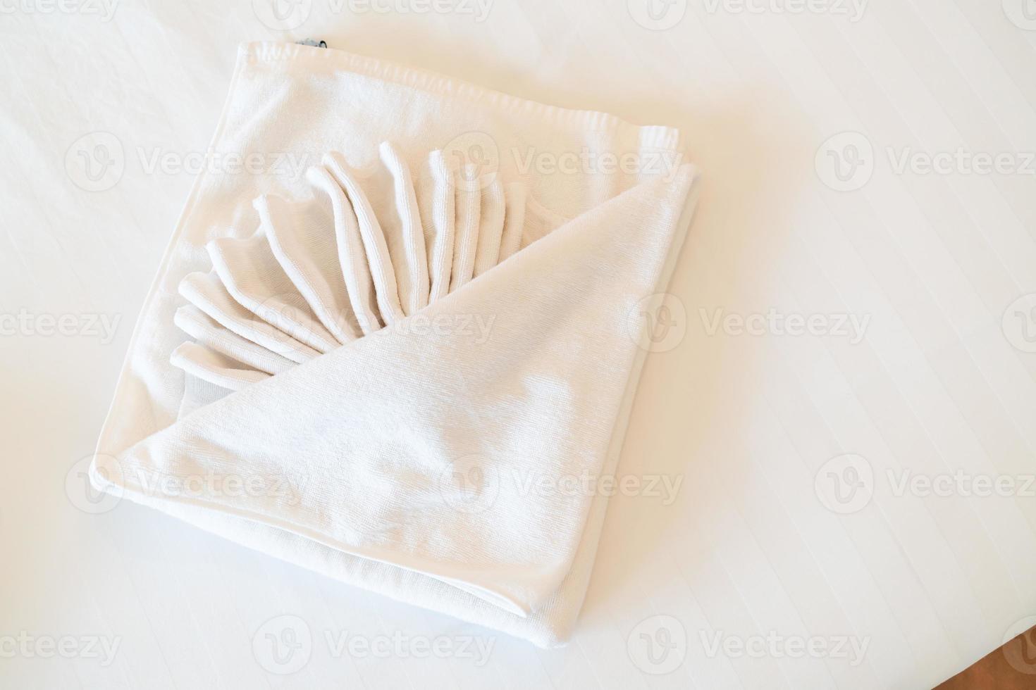 Beautiful folded white towel decoration on bed photo