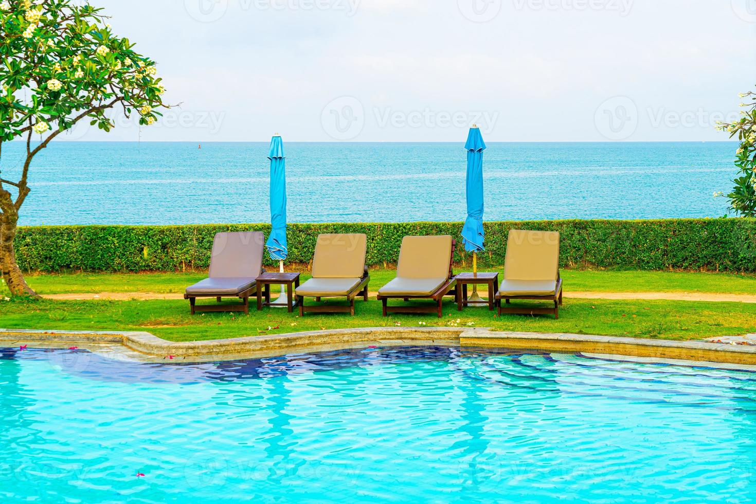 Chair pool and umbrella around swimming pool with ocean sea background photo