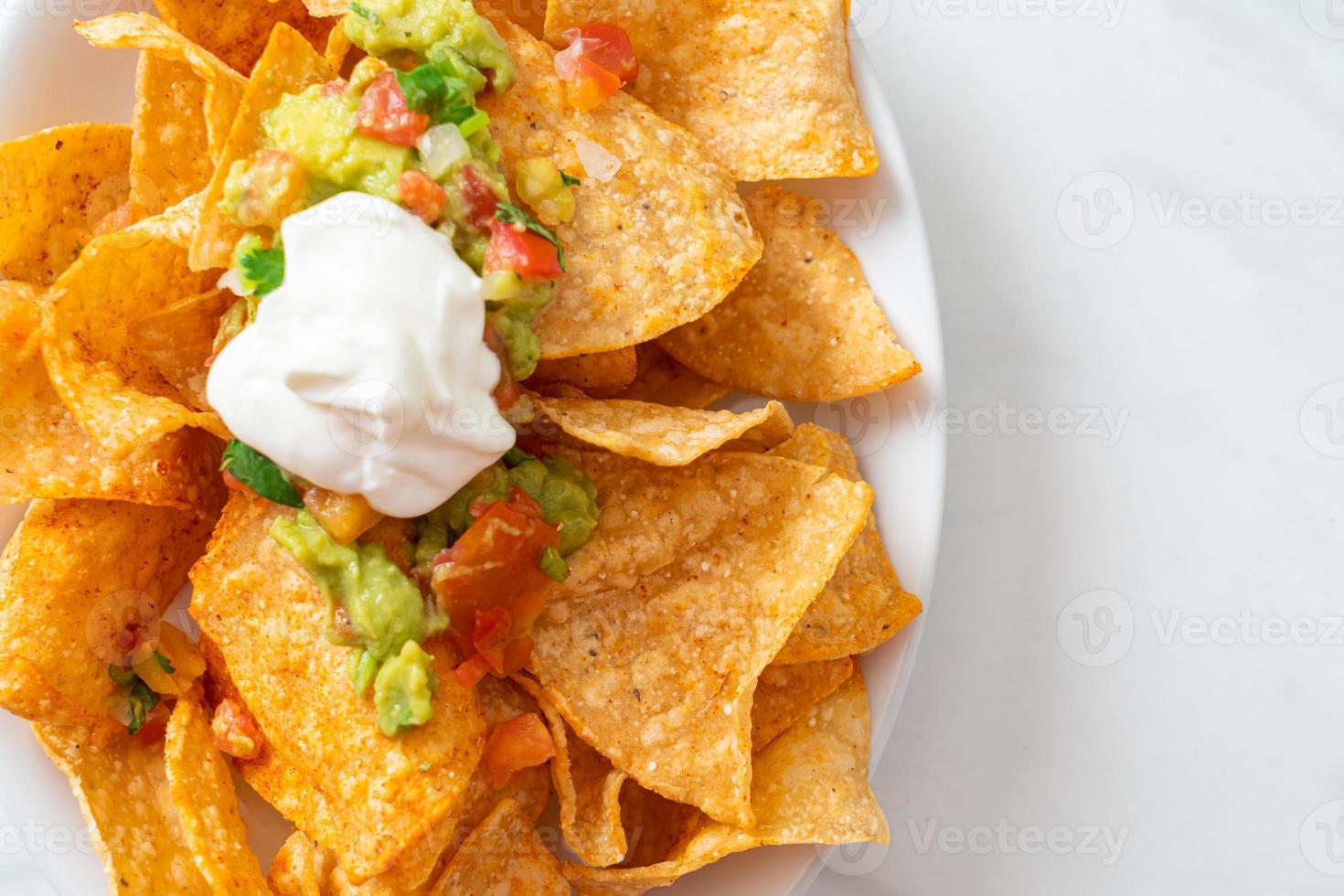 Mexican nachos tortilla chips with jalapeno, guacamole, tomatoes salsa, and dip photo