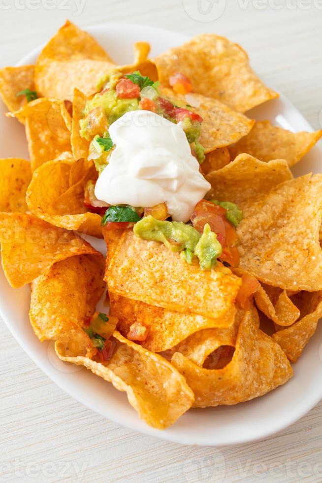 Mexican nachos tortilla chips with jalapeno, guacamole, tomatoes salsa, and dip photo