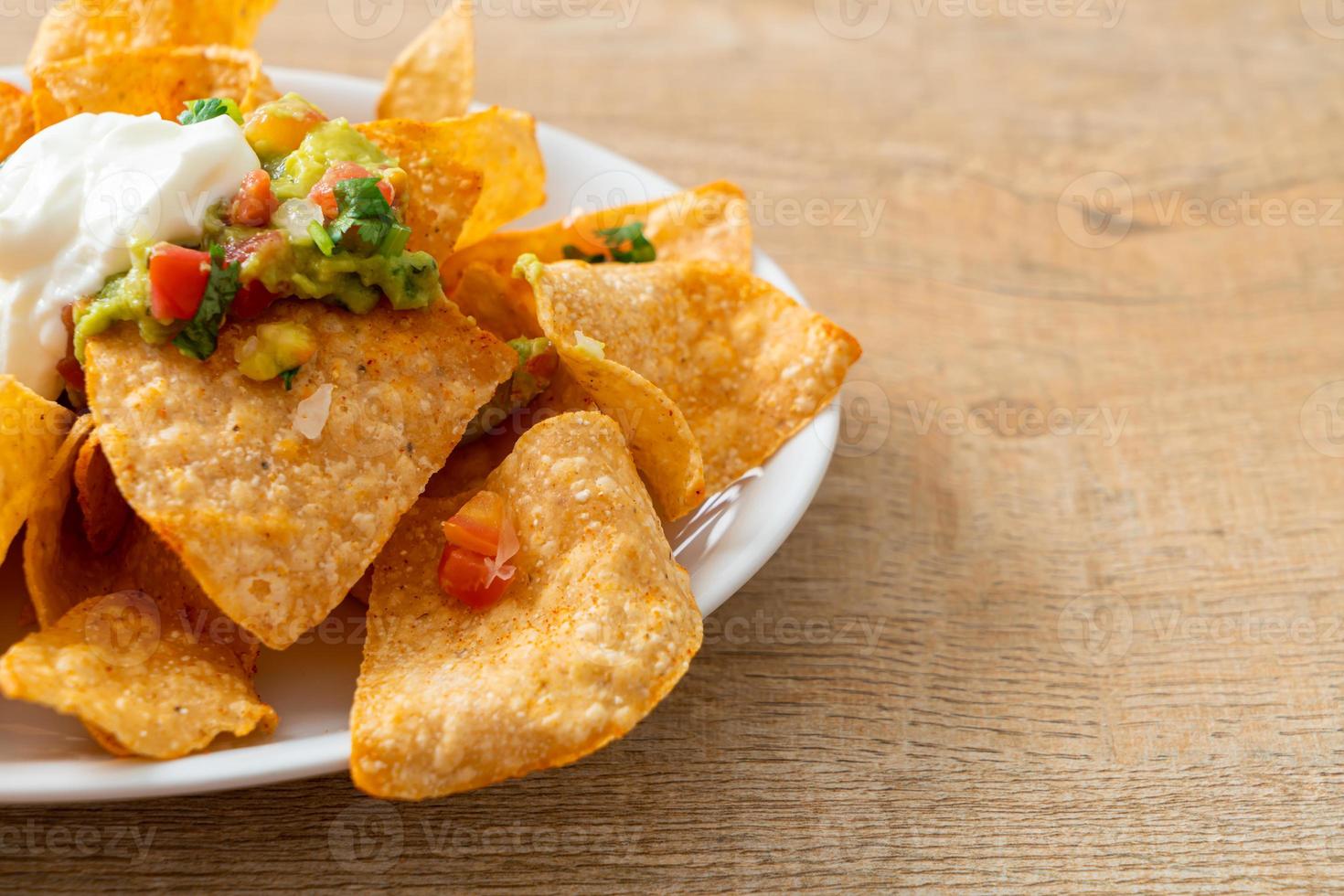 Mexican nachos tortilla chips with jalapeno, guacamole, tomatoes salsa, and dip photo
