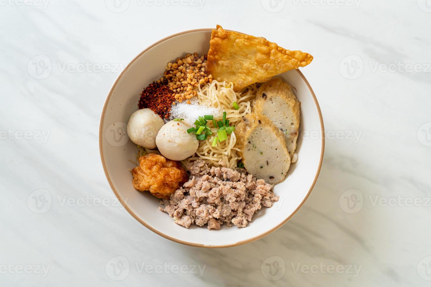 Fideos de huevo picantes con bolas de pescado y bolas de camarones sin sopa - estilo de comida asiática foto