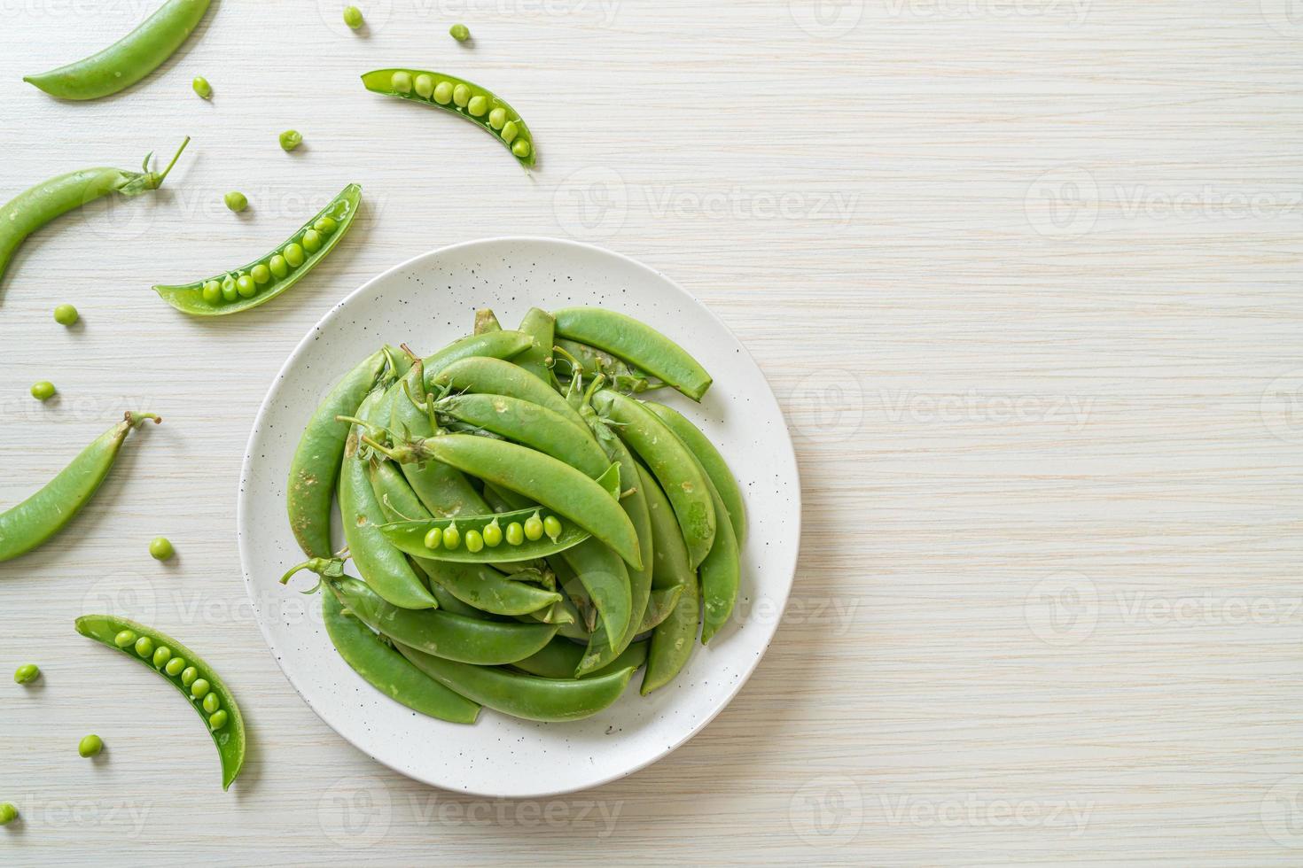 Guisantes verdes dulces frescos en la placa blanca. foto