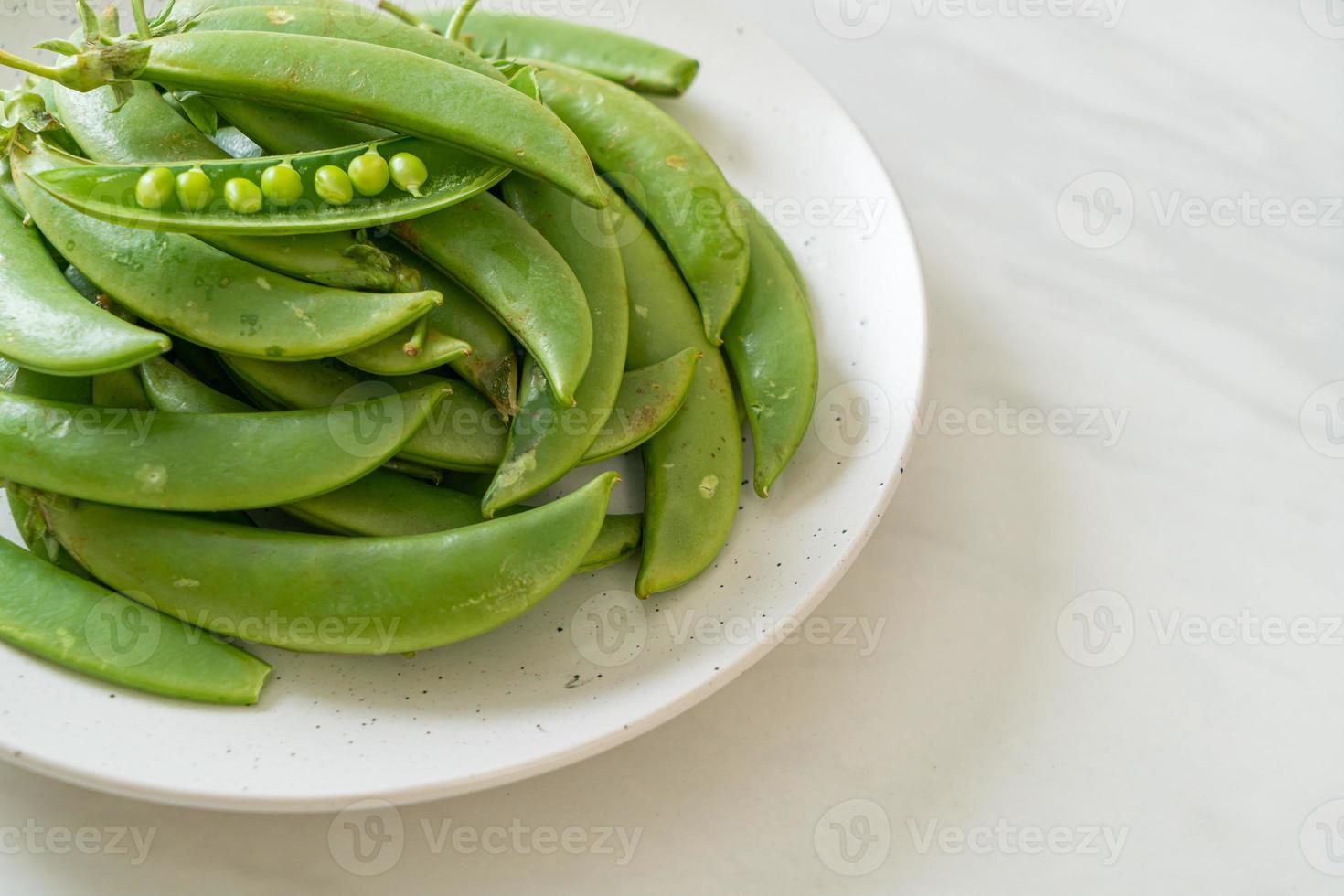 Guisantes verdes dulces frescos en la placa blanca. foto