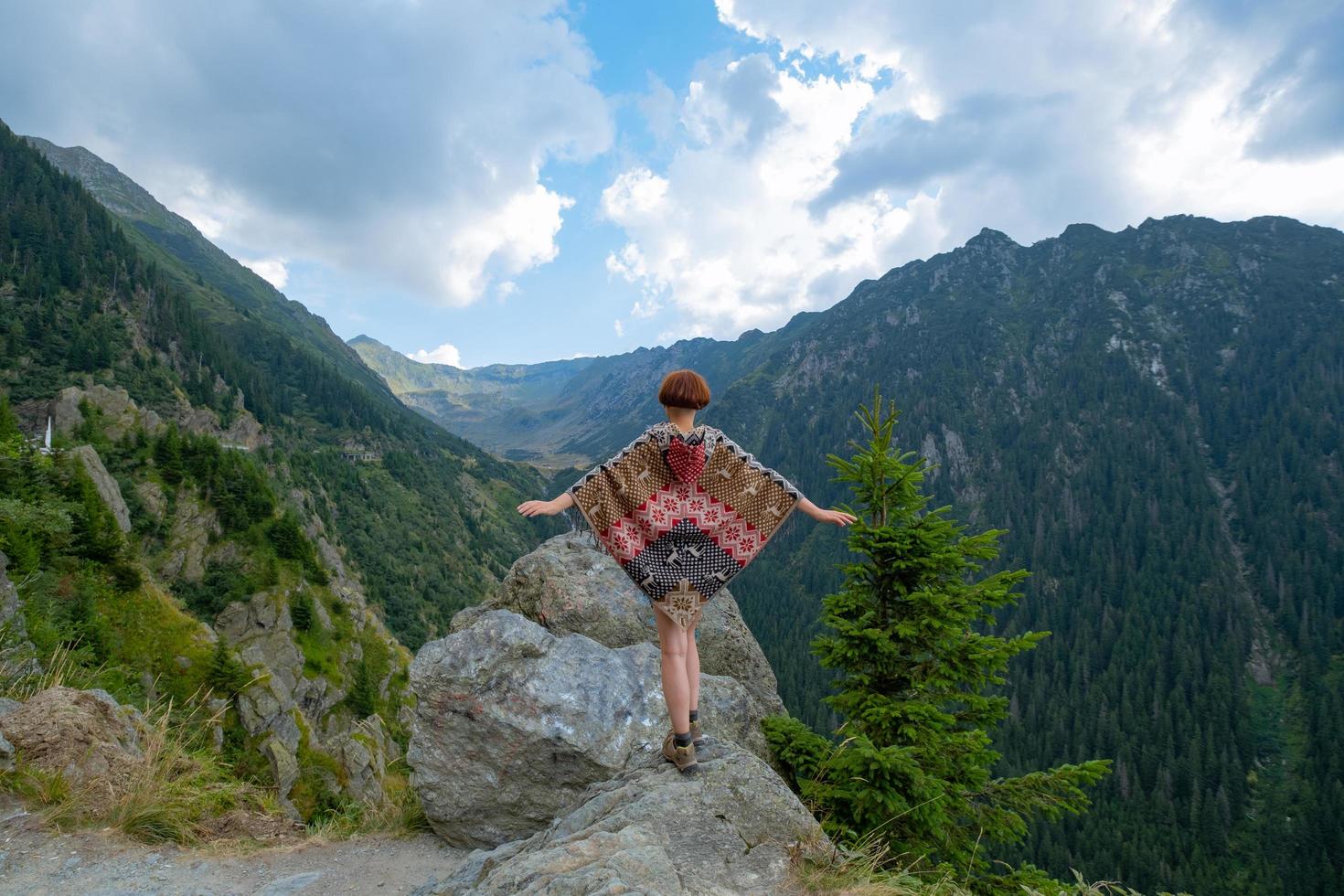 Woman traveler in poncho posing in the mountains photo