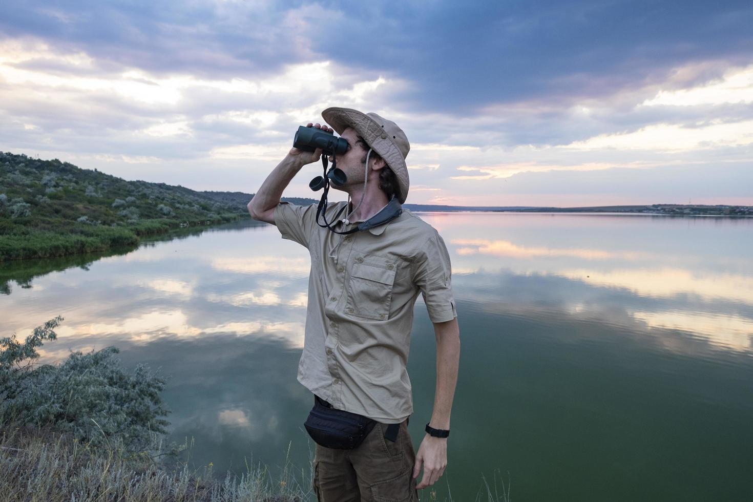 Young male traveler with  binoculars photo
