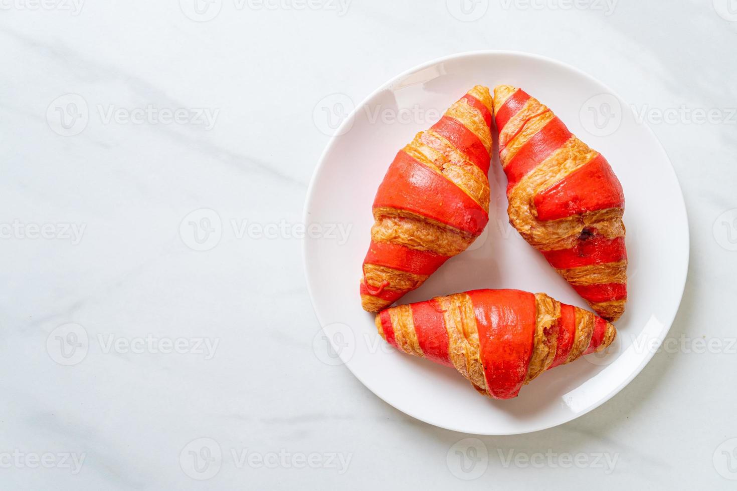 Croissant fresco con salsa de mermelada de fresa en la placa foto