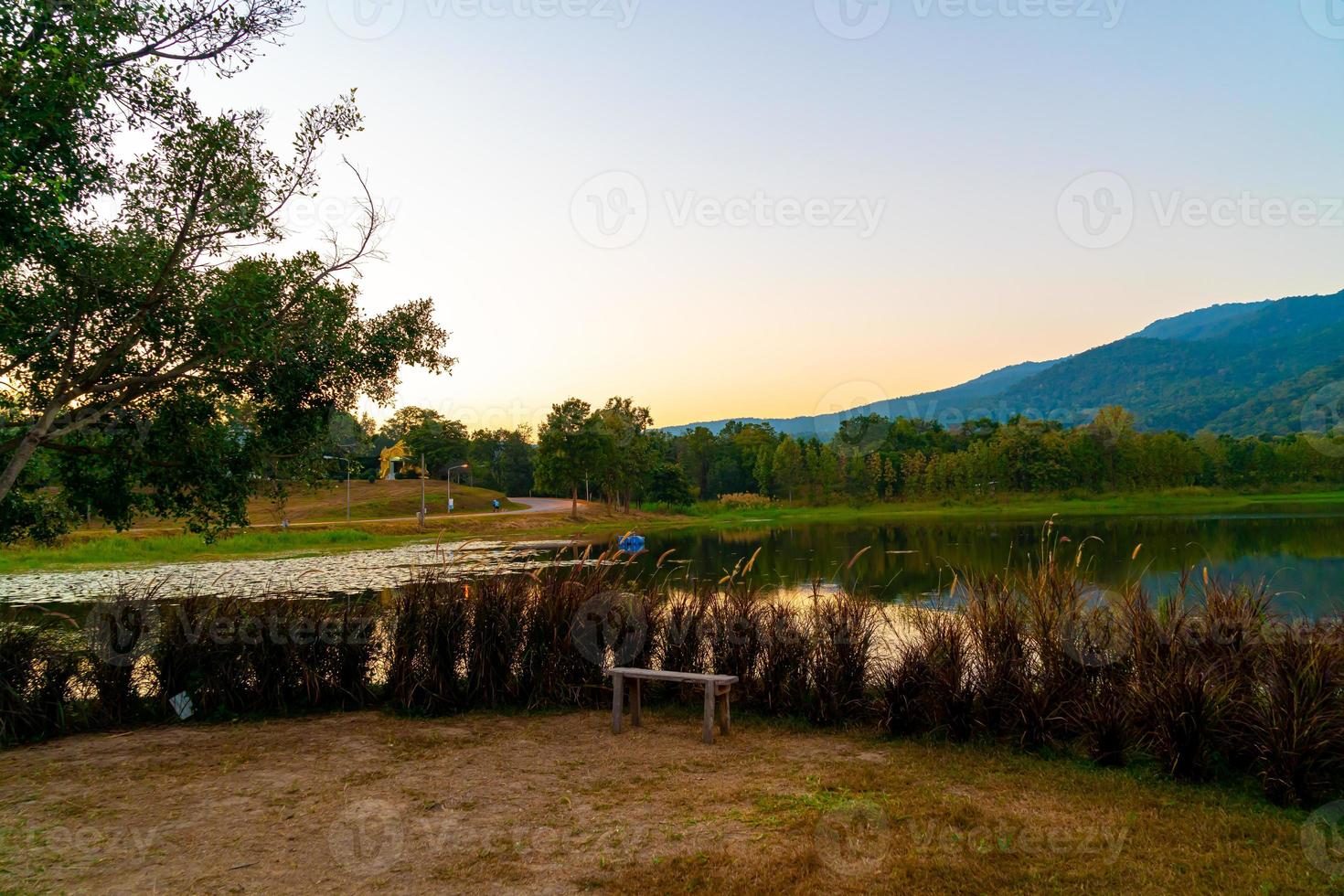 banco de madera con hermoso lago en chiang mai con montaña boscosa y cielo crepuscular en tailandia. foto