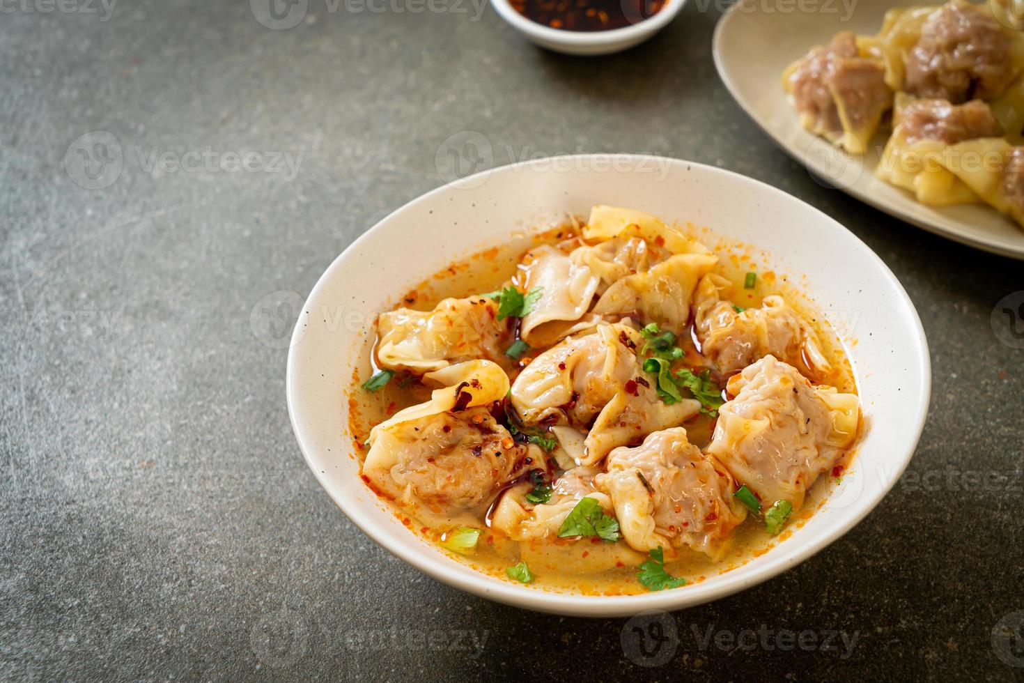 sopa de wonton de cerdo o sopa de albóndigas de cerdo con chile asado - estilo de comida asiática foto