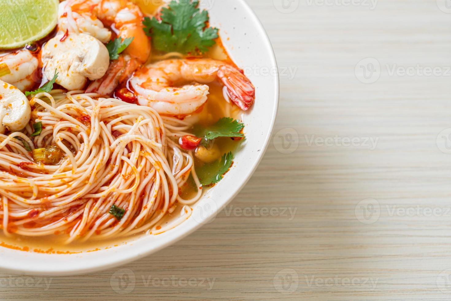 Fideos con sopa picante y camarones en un tazón blanco - tom yum kung - estilo de comida asiática foto