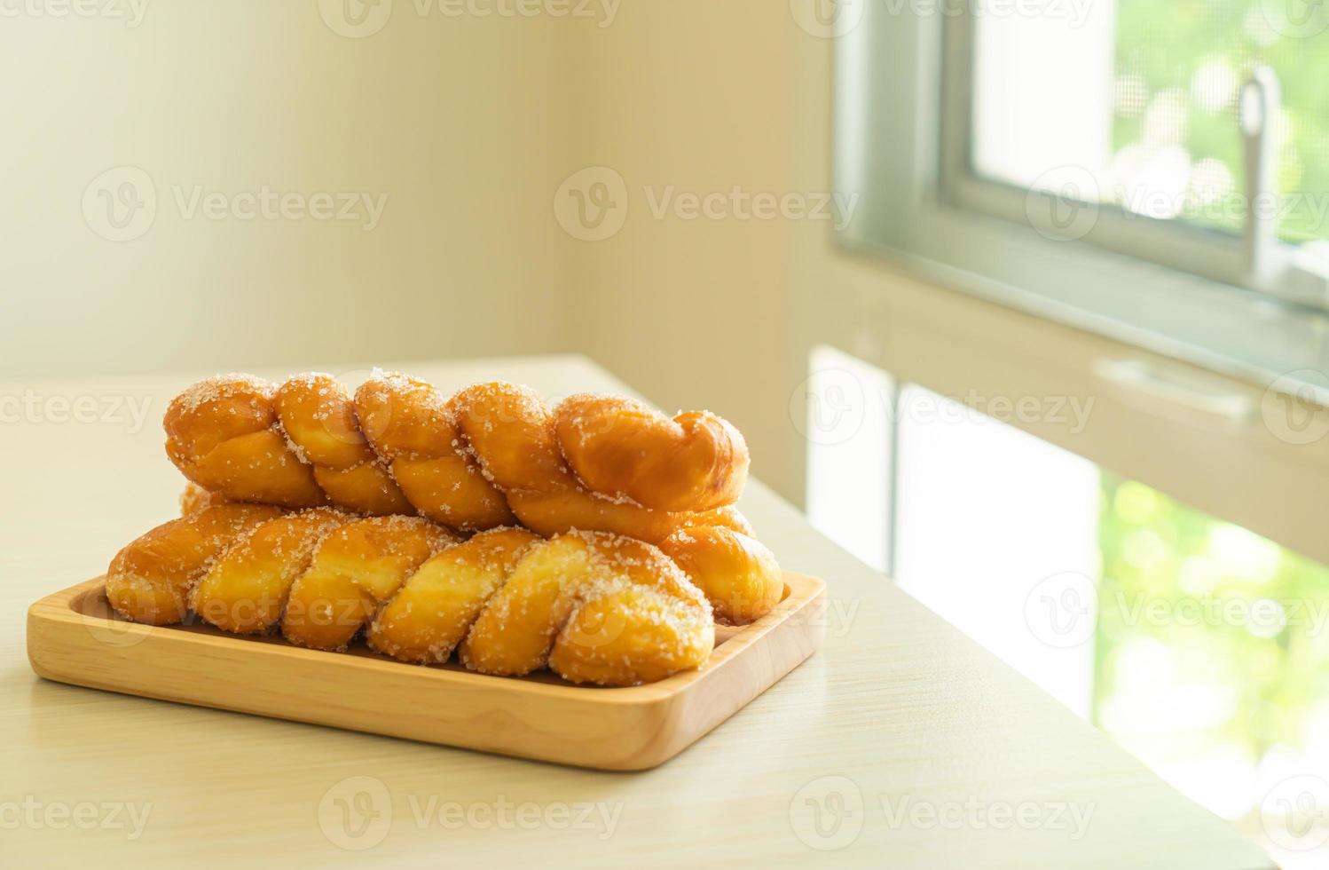 Sugar doughnut in spiral shape on wooden plate photo