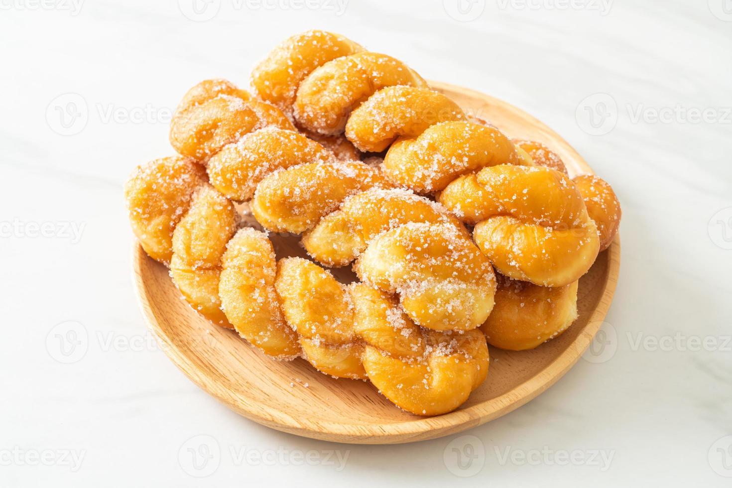 Sugar doughnut in spiral shape on wooden plate photo