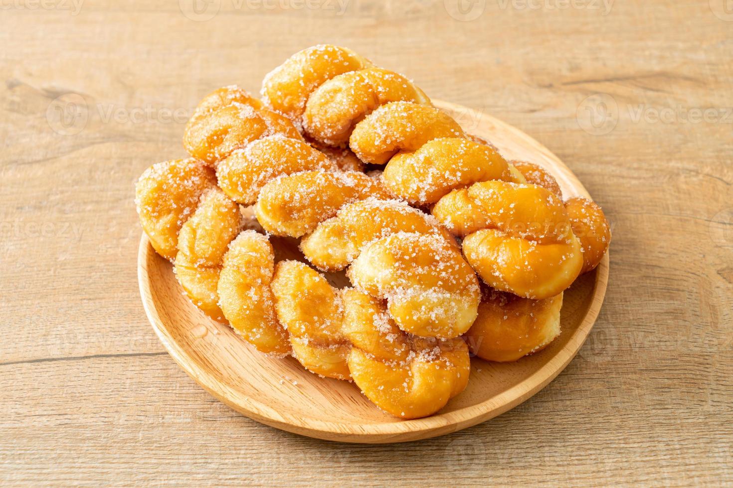 Sugar doughnut in spiral shape on wooden plate photo