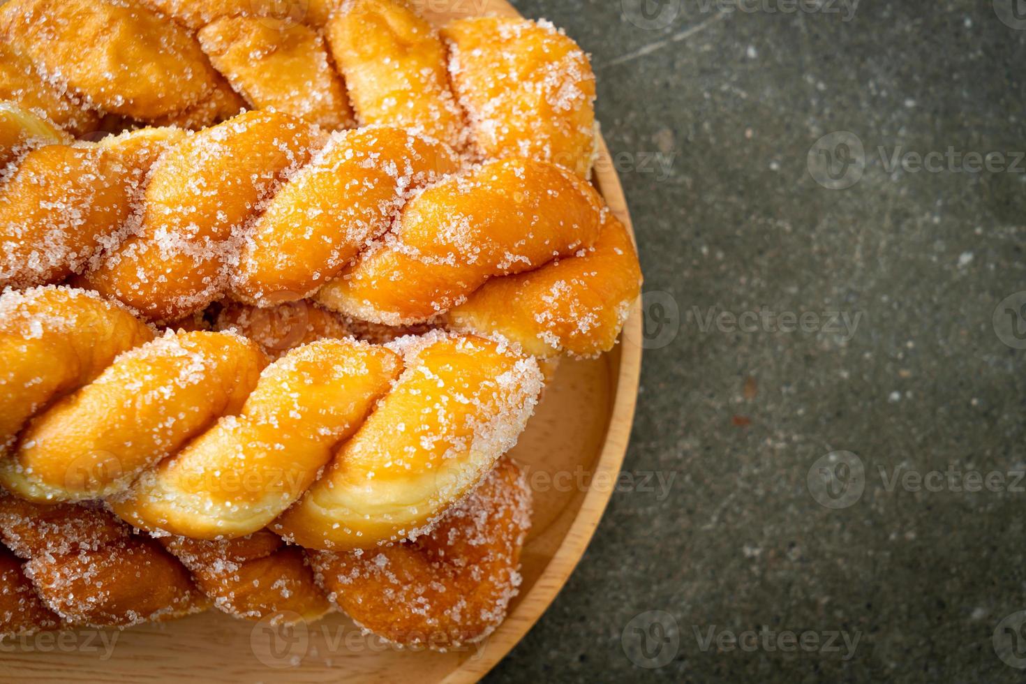 Sugar doughnut in spiral shape on wooden plate photo