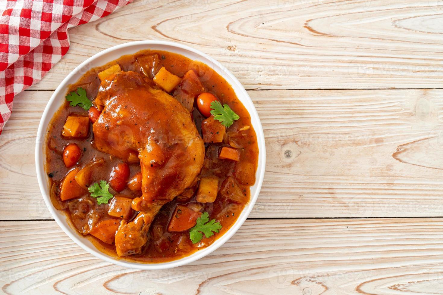 Guiso de pollo casero con tomates, cebollas, zanahorias y patatas en la placa foto