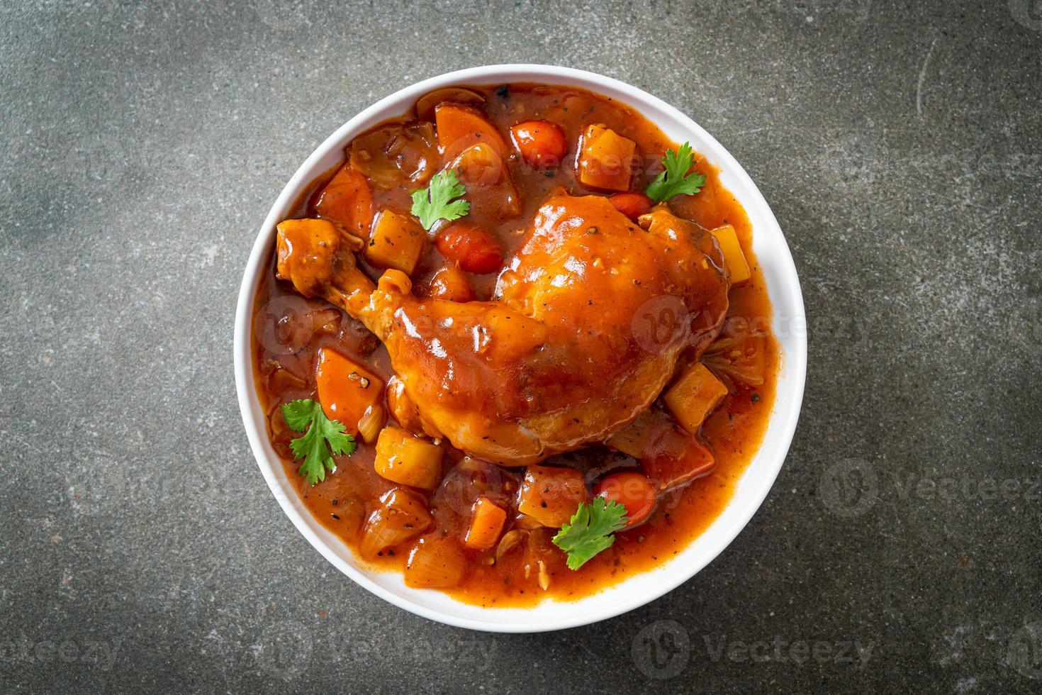 Homemade chicken stew with tomatoes, onions, carrot and potatoes on plate photo