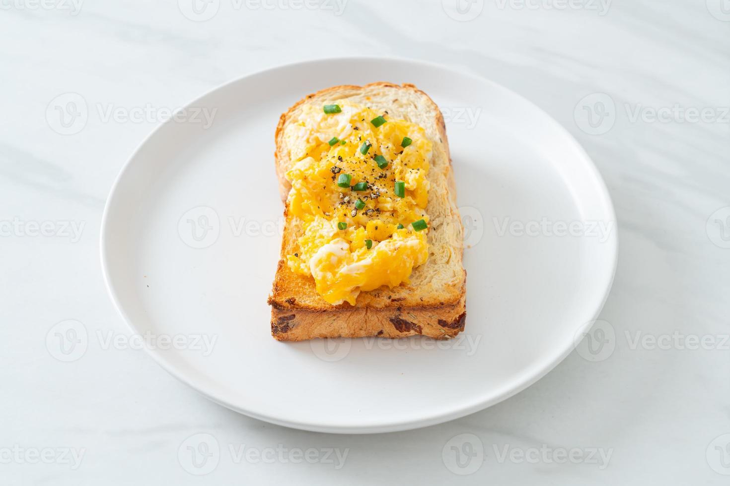 Tostadas de pan con huevos revueltos en la placa blanca. foto