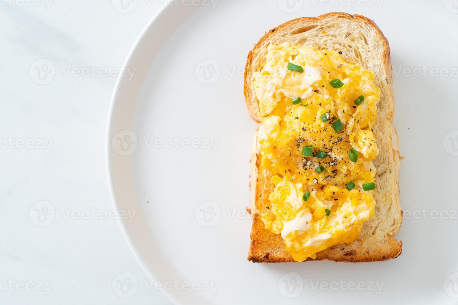 Tostadas de pan con huevos revueltos en la placa blanca. foto