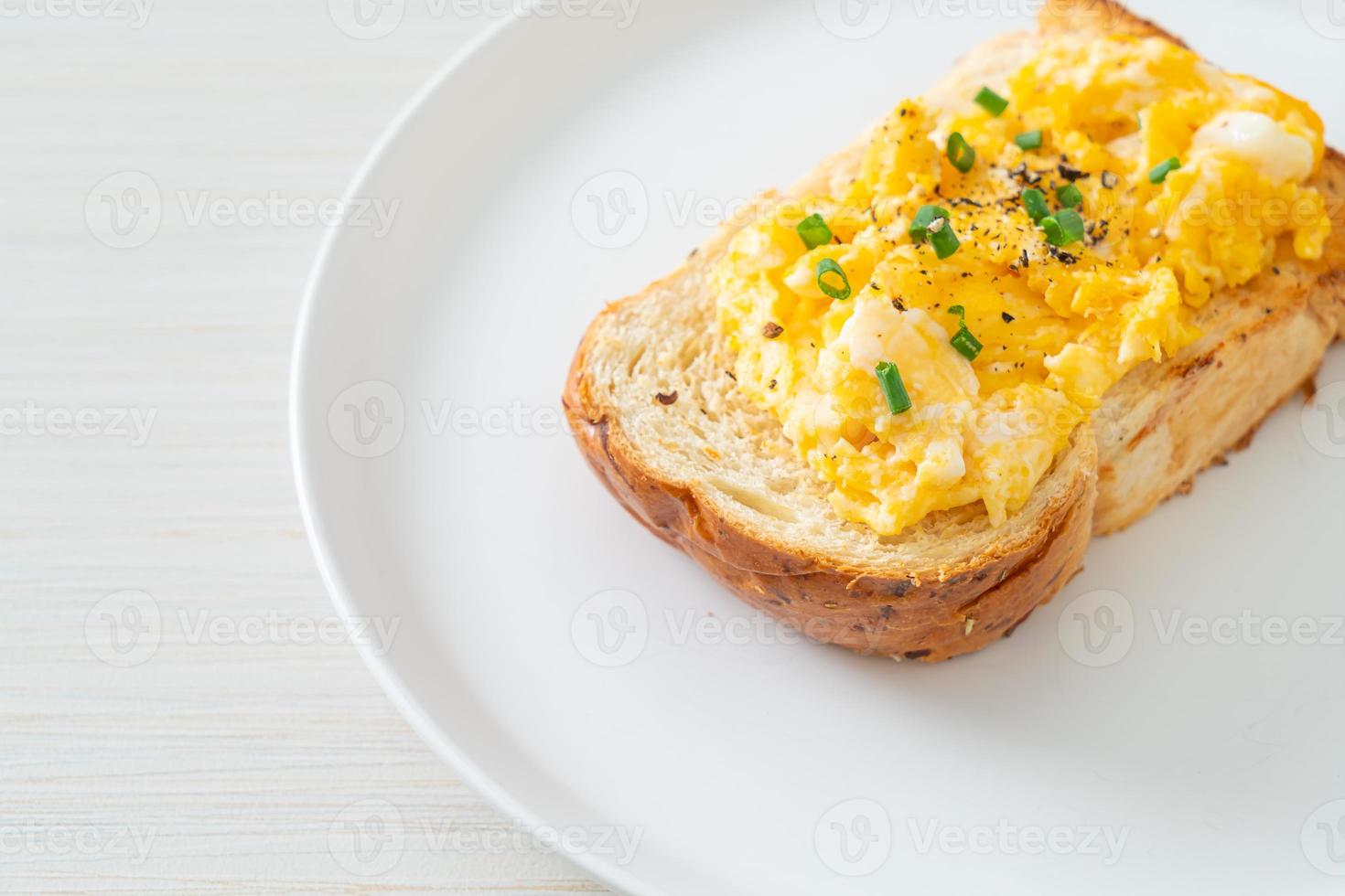 Tostadas de pan con huevos revueltos en la placa blanca. foto