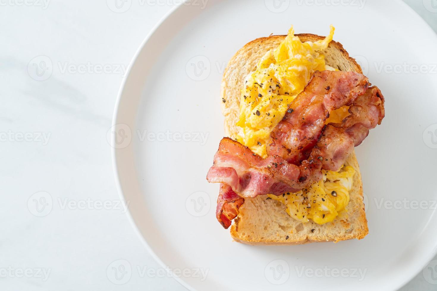 Bread toast with scramble egg and bacon on white plate photo