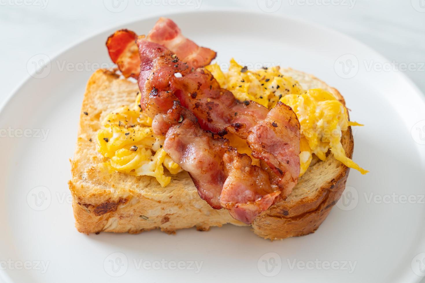 Bread toast with scramble egg and bacon on white plate photo