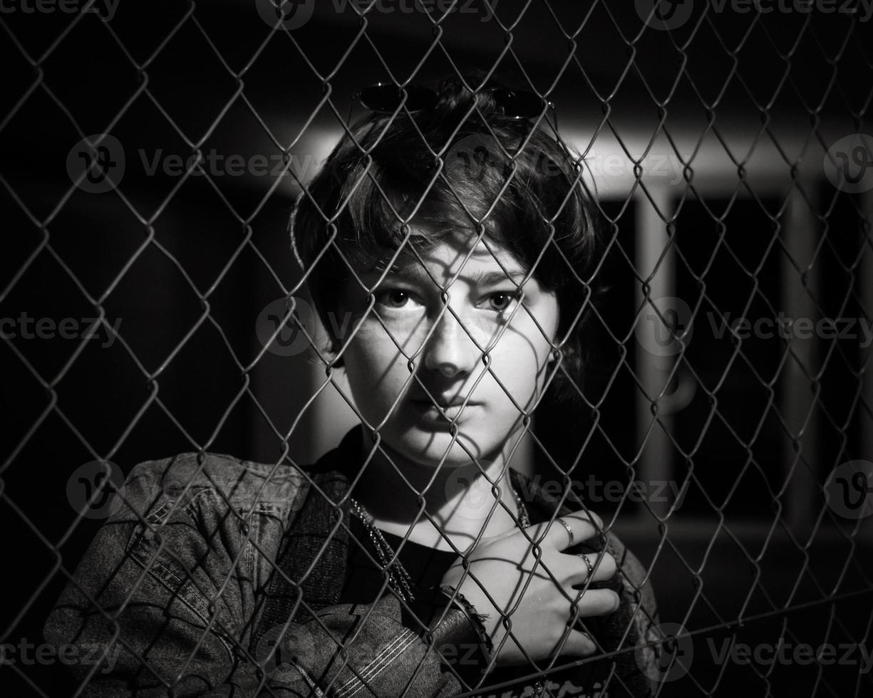 Portrait of a young girl behind the fence photo