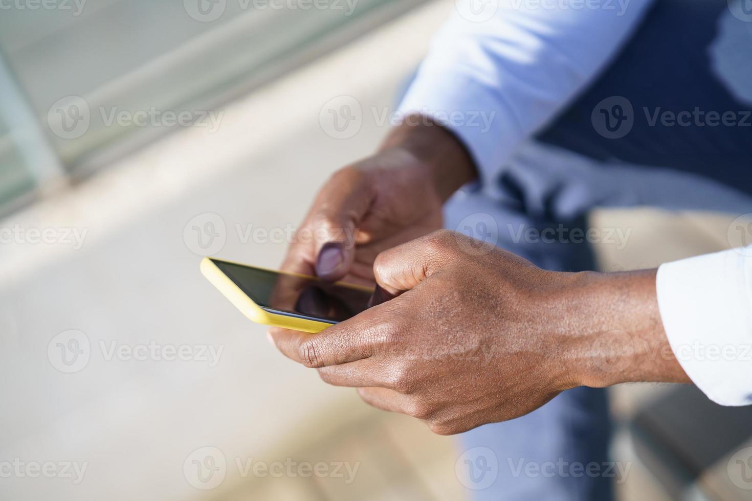 manos de hombre negro irreconocible usando un teléfono inteligente. foto