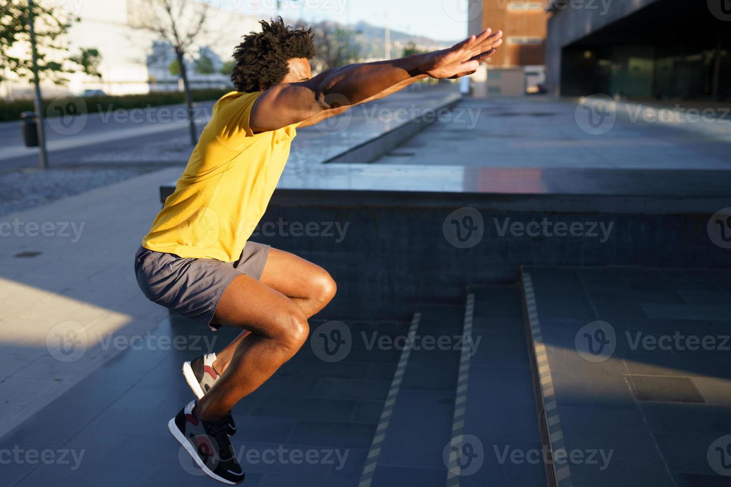 hombre negro haciendo sentadillas con saltar en un escalón. foto