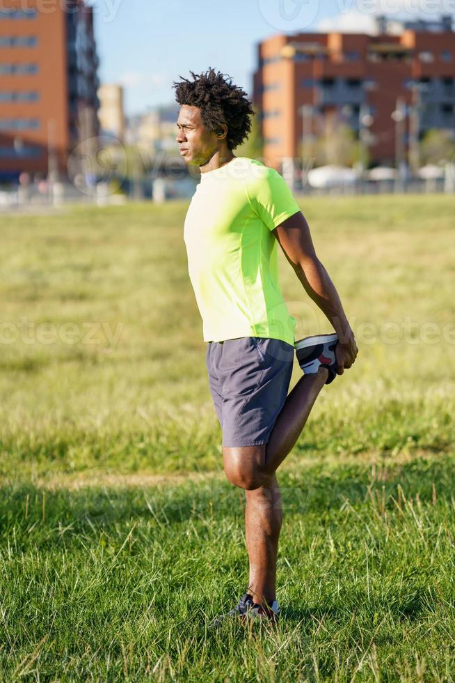 Black man stretching his quadriceps after running outdoors. photo