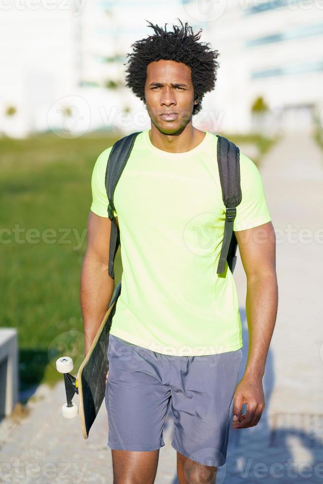 Black man going for a workout in sportswear and a skateboard. photo