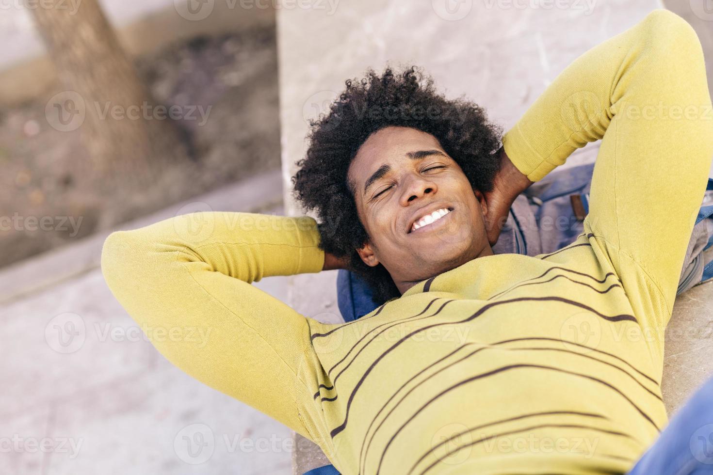 turista negro con pelo afro tirado en el suelo al aire libre. foto